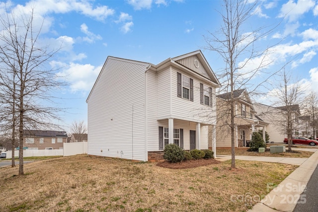 view of home's exterior featuring a lawn, board and batten siding, concrete driveway, and fence