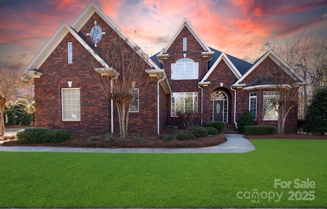 traditional-style home featuring a yard and brick siding