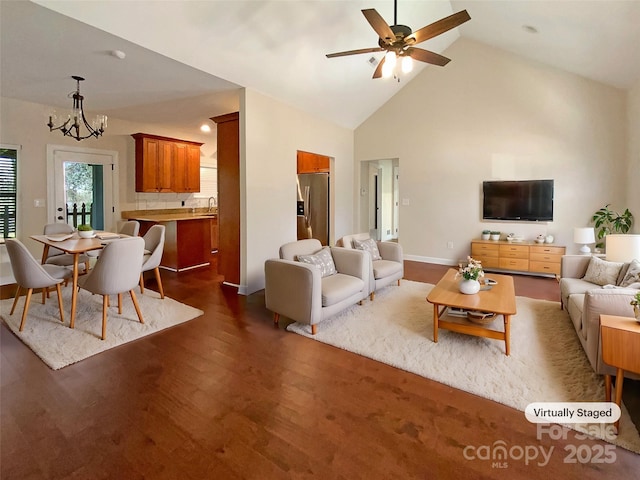 living area featuring baseboards, dark wood-type flooring, high vaulted ceiling, and ceiling fan with notable chandelier