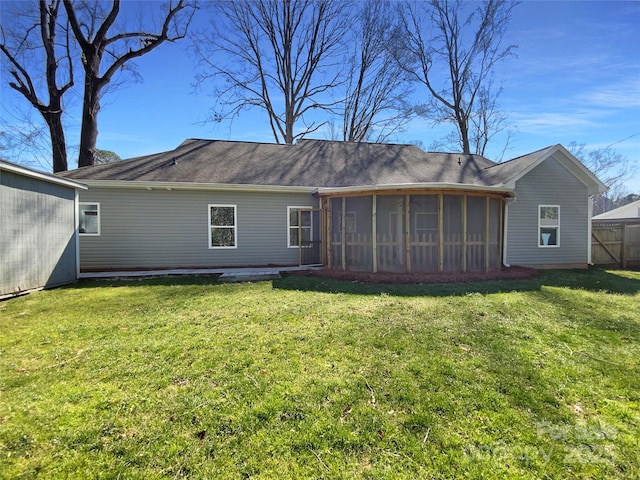 back of property with a sunroom, a lawn, and fence