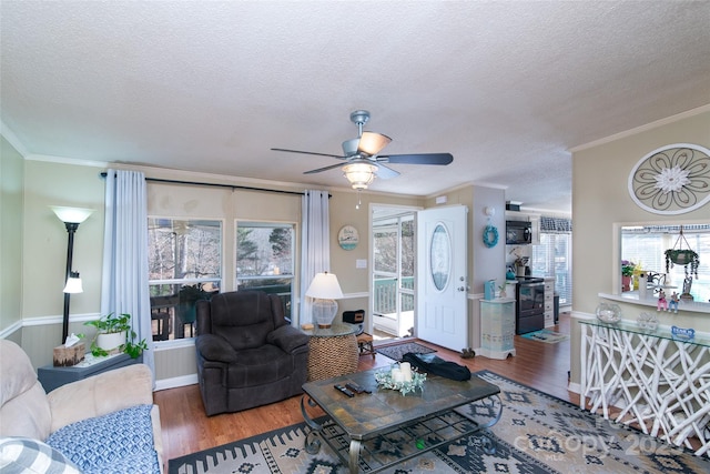 living room featuring a textured ceiling, crown molding, a ceiling fan, and wood finished floors