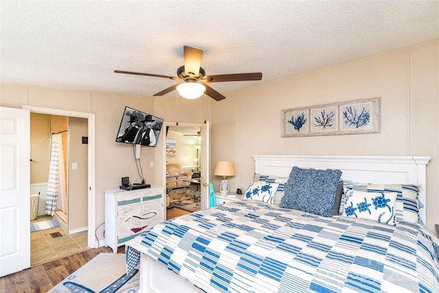 bedroom with a textured ceiling, wood finished floors, a ceiling fan, and a decorative wall