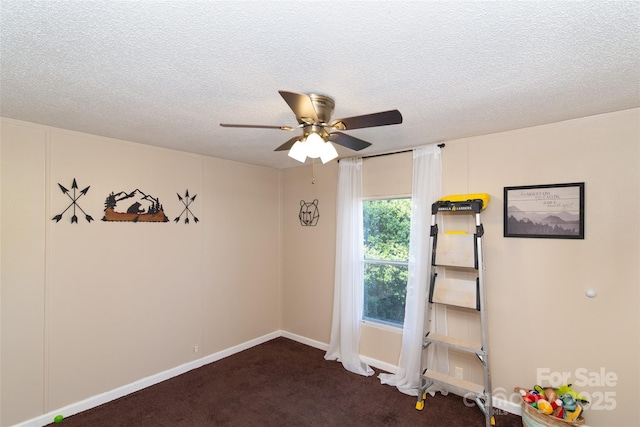 empty room featuring dark carpet, a textured ceiling, and a ceiling fan