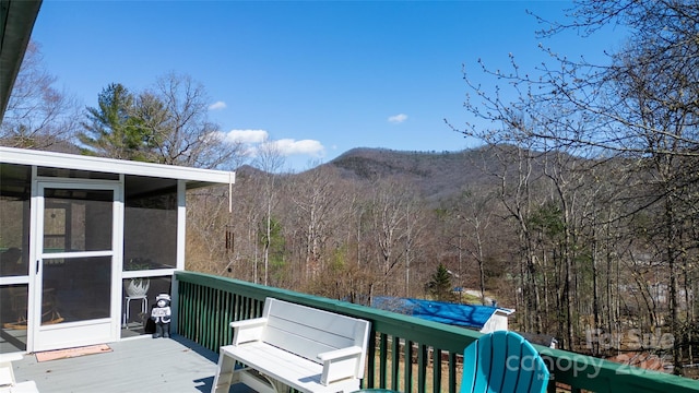 deck with a forest view, a mountain view, and a sunroom