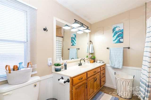 bathroom with vanity, toilet, a shower with curtain, and a wainscoted wall