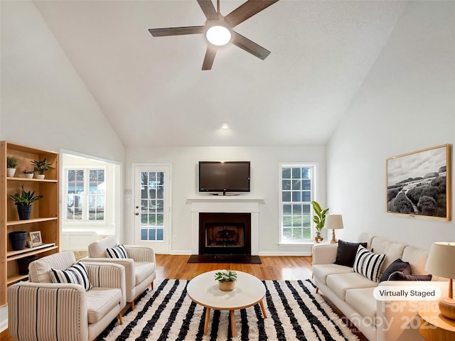 living room with a fireplace with flush hearth, high vaulted ceiling, wood finished floors, and a ceiling fan