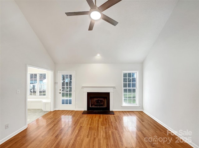 unfurnished living room featuring a fireplace with flush hearth, wood finished floors, baseboards, and ceiling fan