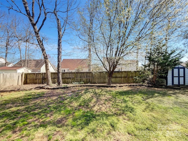 view of yard with a storage shed, a fenced backyard, and an outdoor structure