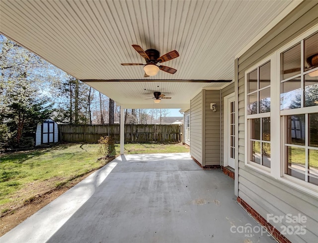 view of patio / terrace with an outbuilding, fence, a shed, and ceiling fan