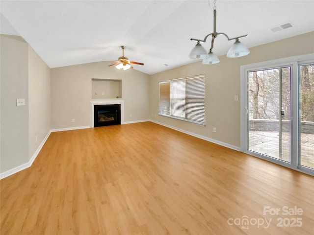 unfurnished living room featuring light wood-style flooring, plenty of natural light, ceiling fan with notable chandelier, and visible vents