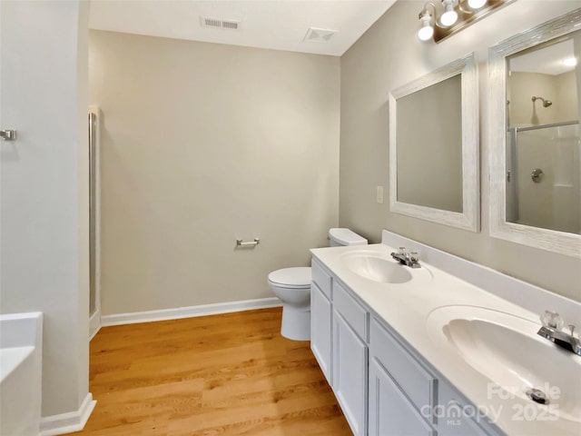 full bathroom featuring an enclosed shower, wood finished floors, visible vents, and a sink