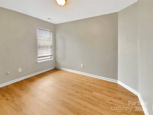 unfurnished room with baseboards, visible vents, and light wood-type flooring