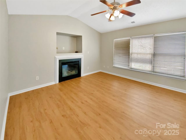 unfurnished living room featuring visible vents, a ceiling fan, wood finished floors, a glass covered fireplace, and lofted ceiling