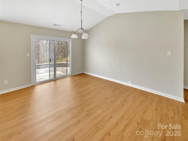 empty room with light wood-type flooring, visible vents, baseboards, a chandelier, and vaulted ceiling