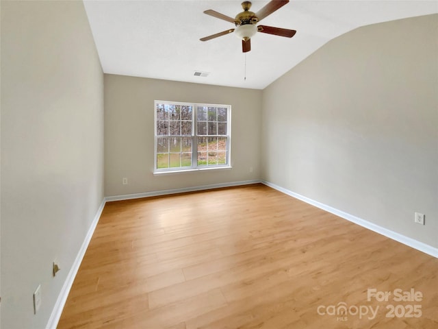 spare room with baseboards, visible vents, ceiling fan, vaulted ceiling, and light wood-type flooring