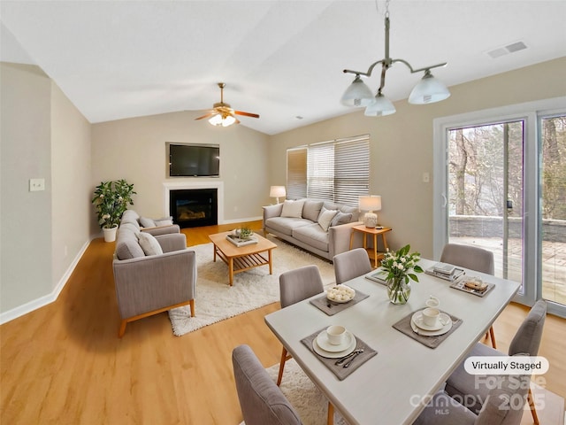 dining area with light wood-type flooring, visible vents, lofted ceiling, a ceiling fan, and baseboards