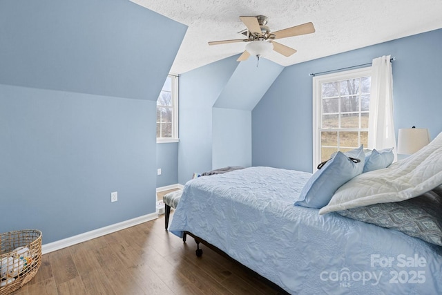 bedroom with multiple windows, wood finished floors, baseboards, and a textured ceiling