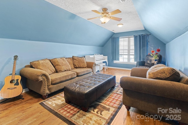 living room featuring vaulted ceiling, baseboards, a textured ceiling, ceiling fan, and wood finished floors