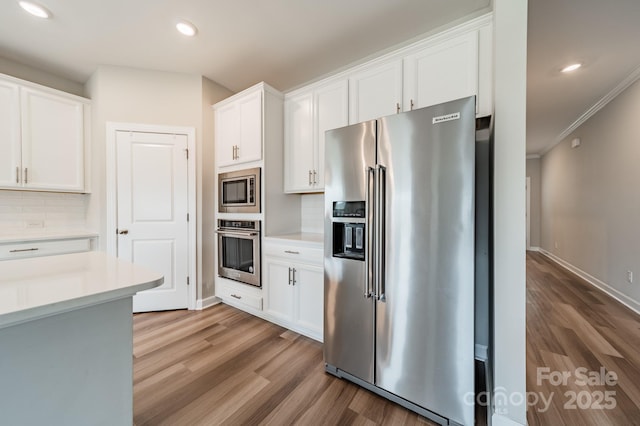 1819 Lotus Ln, Denver, NC 28037 - kitchen featuring appliances with stainless steel finishes, light wood-type flooring, backsplash, white cabinetry, and light countertops