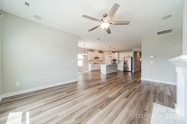 1819 Lotus Ln, Denver, NC 28037 - unfurnished living room with a ceiling fan, light wood finished floors, baseboards, a chandelier, and a fireplace with flush hearth