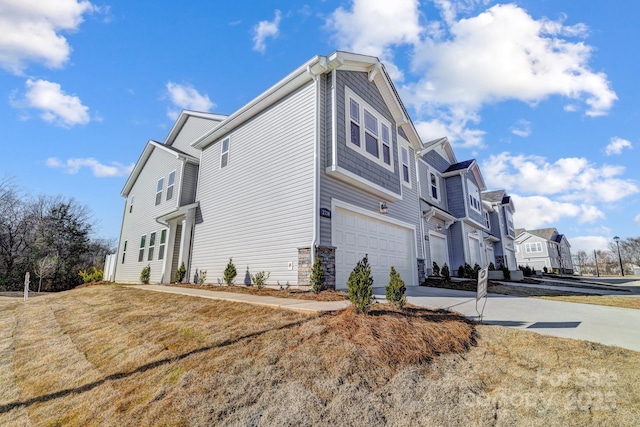 view of property exterior featuring stone siding, an attached garage, and driveway