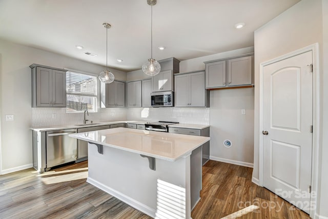 kitchen with visible vents, gray cabinets, a sink, appliances with stainless steel finishes, and dark wood-style flooring