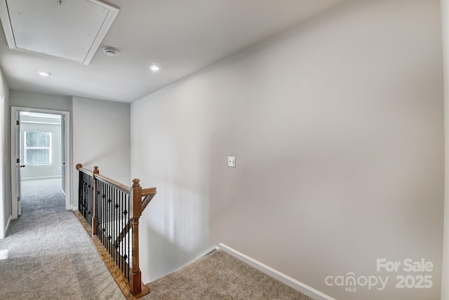 hallway featuring carpet, attic access, an upstairs landing, and baseboards