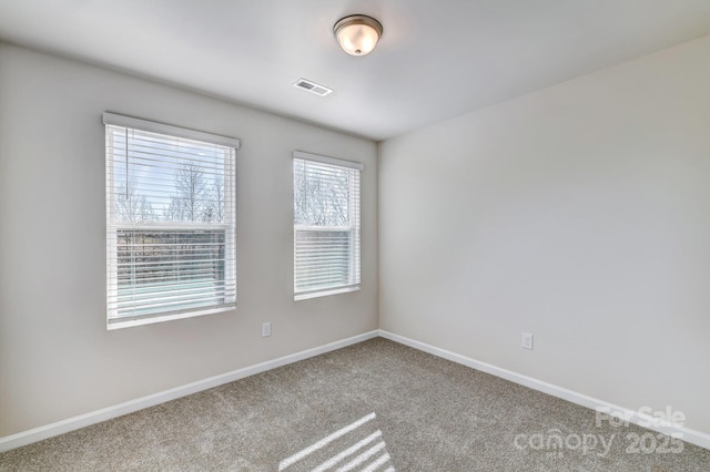 unfurnished room with carpet flooring, visible vents, and baseboards