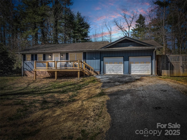 ranch-style home featuring aphalt driveway, a garage, a front lawn, and fence