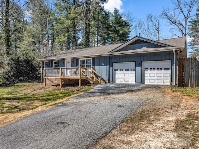 ranch-style house with aphalt driveway, fence, and a garage