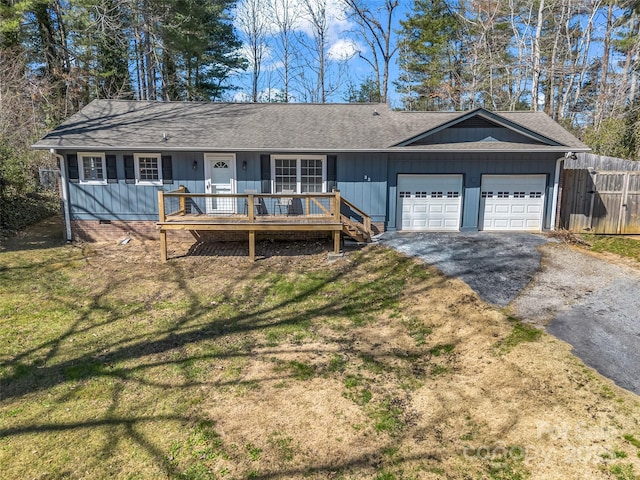 ranch-style house featuring aphalt driveway, an attached garage, fence, and a front lawn