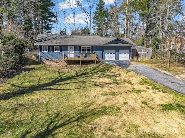 ranch-style home featuring a deck, aphalt driveway, an attached garage, and a front yard