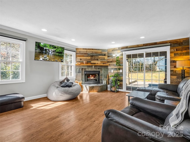 living area featuring baseboards, wood walls, recessed lighting, a fireplace, and wood finished floors