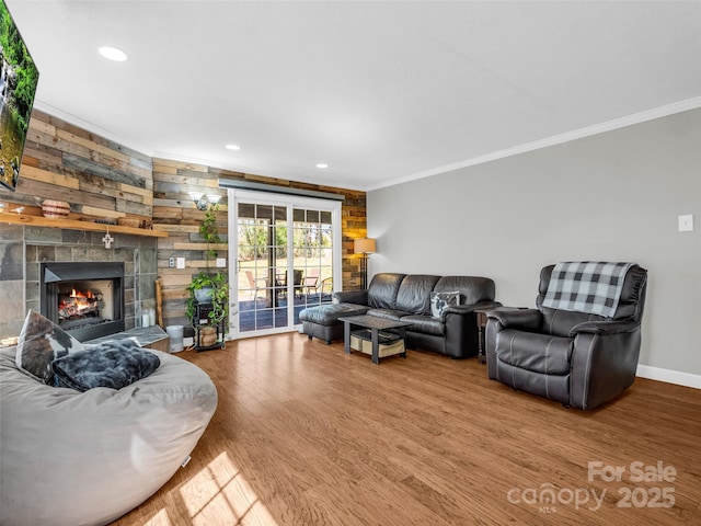 living room featuring wood finished floors, recessed lighting, a fireplace, crown molding, and baseboards