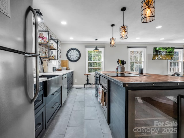 kitchen with wood counters, recessed lighting, stainless steel appliances, wine cooler, and hanging light fixtures