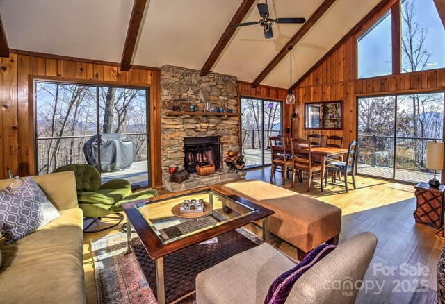 living room featuring a wealth of natural light, wood walls, and ceiling fan