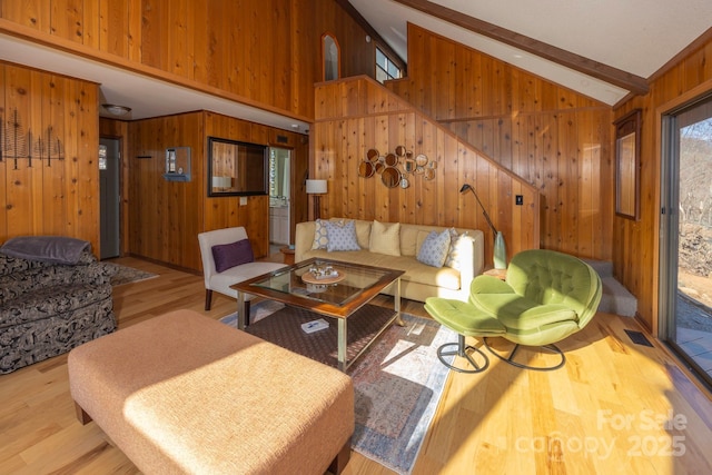 living area with beamed ceiling, wooden walls, wood finished floors, and high vaulted ceiling