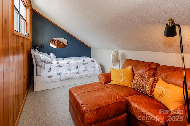 bedroom featuring wood walls, a textured ceiling, lofted ceiling, and carpet