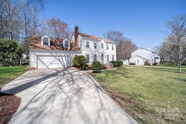 view of front of property with a chimney, driveway, an attached garage, and a front lawn