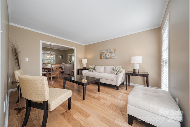 living area with light wood-type flooring, baseboards, and ornamental molding