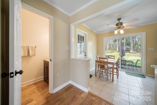 dining area featuring light wood-style floors, baseboards, a ceiling fan, and crown molding