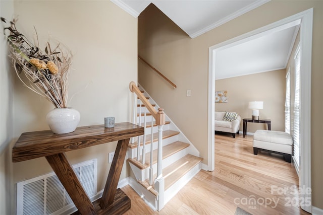 stairway with crown molding, wood finished floors, and baseboards