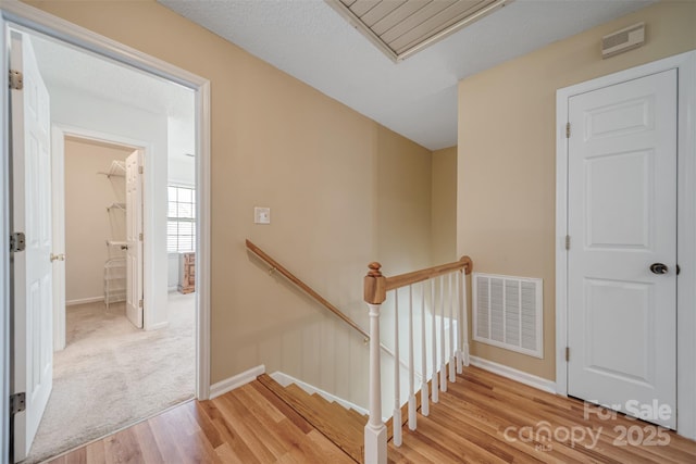 stairway featuring visible vents, attic access, baseboards, and wood finished floors