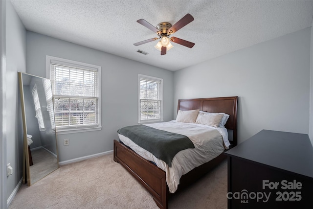 bedroom featuring visible vents, baseboards, ceiling fan, light colored carpet, and a textured ceiling