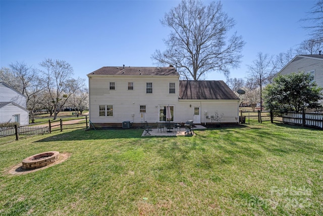 rear view of house with a fenced backyard, a patio, a fire pit, and a yard