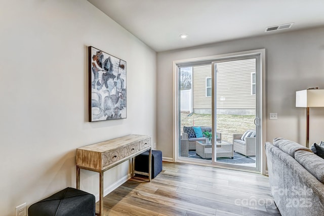 living area featuring visible vents, baseboards, and wood finished floors