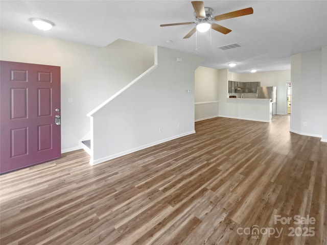 unfurnished living room featuring stairs, wood finished floors, visible vents, and a ceiling fan