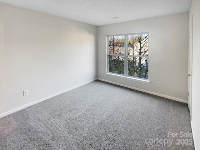 unfurnished room with visible vents, baseboards, carpet floors, and a textured ceiling