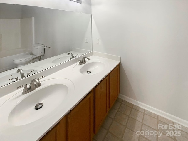 bathroom with a sink, toilet, and double vanity