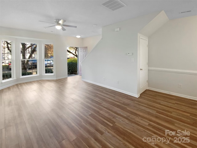 spare room with a ceiling fan, wood finished floors, visible vents, and baseboards